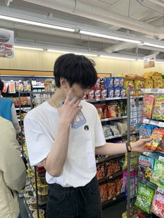 a man is talking on his cell phone while shopping in a grocery store with other people