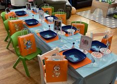 the table is set with blue and orange plates, napkins, and paper bags