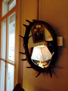 a mirror hanging on the side of a wall next to a table with a lamp