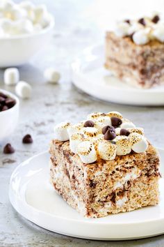 a piece of cake on a plate with chocolate chips and marshmallows around it