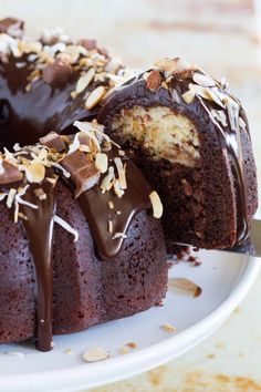 a bundt cake with chocolate frosting and nuts on top, cut in half