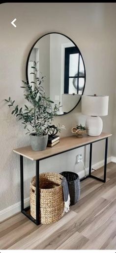 a mirror on the wall above a table with a potted plant next to it