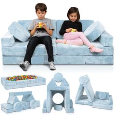 two children sitting on a blue couch with toys in front of them and the child is playing