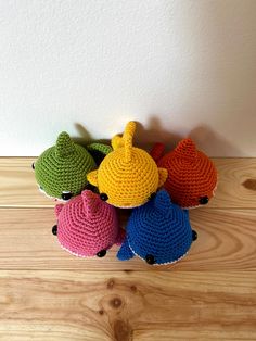 small crocheted teapots are lined up on a wooden table with white wall in the background