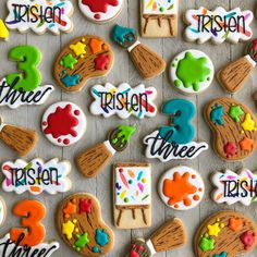 decorated cookies are displayed on a table with the names and numbers painted in different colors