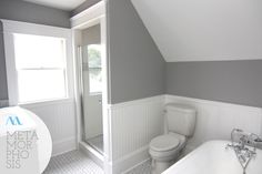 a white bath tub sitting under a window next to a toilet and sink in a bathroom