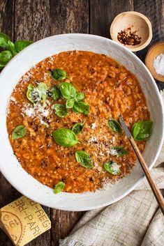 a white bowl filled with tomato soup and basil