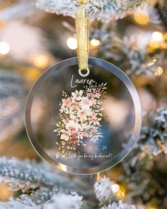 a glass ornament hanging from a christmas tree with flowers on it's side