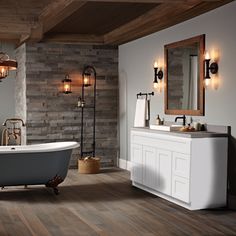 a bathroom with wood flooring and stone walls, including a claw foot bathtub