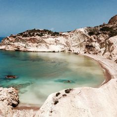 a body of water surrounded by white rocks and blue sky in the middle of nowhere