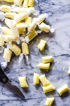 chopped up pieces of cheese sitting on top of a marble counter next to a knife