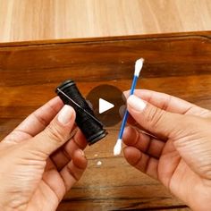 two hands are holding toothbrushes in front of a wooden box with a hole