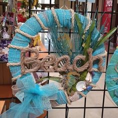 a blue wreath with the word beach hanging from it's side on a wire fence