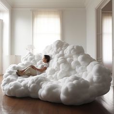 a woman laying on top of a cloud like bed