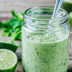 a jar filled with green liquid next to sliced limes