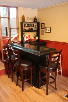 there is a bar with four stools at the top and an open shelf above it