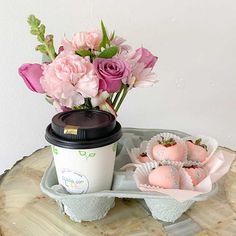 a coffee cup and some pink flowers on a table with donut holes in it