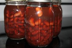 two jars filled with pickled strawberries on top of a black table next to a stove