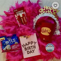 a birthday card, candy, and other items are laid out on a fluffy pink blanket