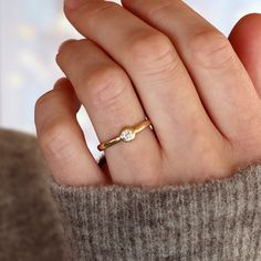 a woman's hand with a diamond ring on her finger, wearing a sweater