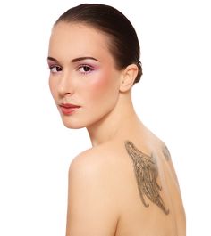 a woman with an angel tattoo on her shoulder and chest is looking at the camera