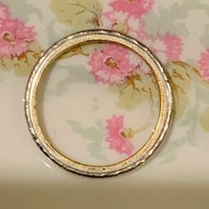 a gold ring sitting on top of a floral wallpapered tablecloth with pink flowers