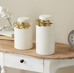 two white vases sitting on top of a wooden table next to an alarm clock