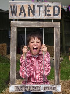 a young boy is holding up a wanted sign in front of his face and the words wanted behind him