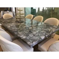 a marble dining table surrounded by white chairs