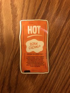 an orange sticker with the words hot on it sitting on top of a wooden table