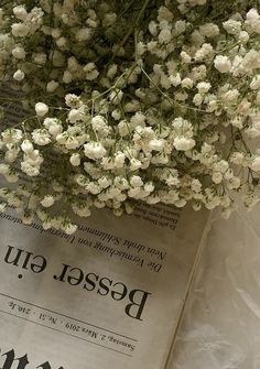 a bunch of white flowers sitting on top of a newspaper with the word bead gut written in russian