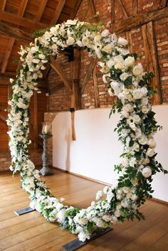 a wedding arch decorated with white flowers and greenery in an old barn setting for a ceremony