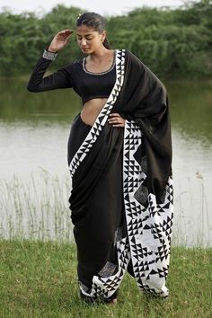 Black saree in taffeta base with black and white prism print on the pallu. Paired with long sleeves embellished neckline padded blouse.
Components: 2
Pattern: Print
Type Of Work: Prism
Neckline: Scoop
Sleeve Type: Full
Fabric: Taffeta
Color: Black
Other Details: 
Attached lining
Padded blouse
Model height: 5ft 8inches, wearing size S
Length:
Blouse: 14inches
Saree: 45inches
Disclaimer: This product is exclusively hand crafted using multiple techniques, individually handled at different stages, a Bollywood Style Black Cotton Silk Pre-draped Saree, Elegant Party Blouse Piece With Printed Motifs, Semi-stitched Blouse Piece With Printed Motifs For Party, Party Blouse Piece With Traditional Drape And Printed Motifs, Party Semi-stitched Blouse Piece With Printed Motifs, Festive Party Blouse With Printed Motifs, Bollywood Style Blouse With Printed Motifs For Party, Bollywood Party Blouse With Printed Motifs, Party Saree With Printed Motifs In Traditional Drape