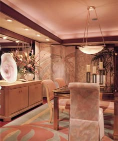 the dining room is decorated in pink and gold tones with an elegant chandelier hanging from the ceiling