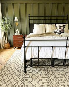 a bed with white sheets and pillows on top of it in a room that has green walls