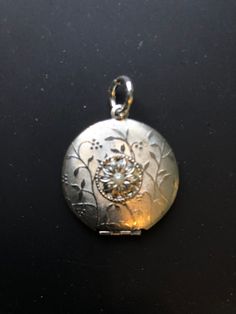 1950s brushed and etched silver tone locket: This sweet dual photo locket has a brushed and etched surface with a floral design. It is centered with a bloom which is in turn centered with a glass pearl. It is  1 1/8 in. in diameter. Vintage Nickel Free Antique Silver Locket Necklace, Vintage Antique Silver Nickel-free Locket Necklace, Antique Silver Vintage Charm Locket Necklace, Vintage Antique Silver Locket Necklace Nickel Free, Antique Silver Locket Necklace With Vintage Charm, Vintage Silver Locket Necklace With Round Pendant, Antique Silver Locket Necklace Nickel Free, Antique Silver Locket Necklace For Vintage Collection, Vintage Medallion Jewelry With Flower Charm