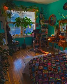 a woman sitting on the floor in a bedroom next to a bed with a colorful bedspread