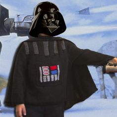 a young boy dressed as darth vader in front of a star wars scene