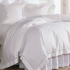 a bed with white sheets and pillows in a room