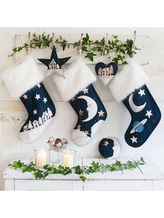 christmas stockings hanging on a wall with candles and greenery