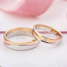 two gold wedding rings sitting next to each other