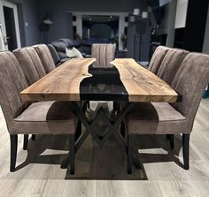 a wooden table with six chairs around it in a room that has hardwood floors and gray walls