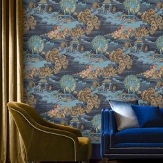 a blue couch sitting next to a chair in front of a wallpapered wall