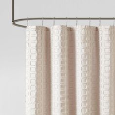 a white shower curtain hanging from a metal rod