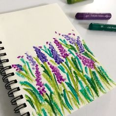 a notebook with crayons and markers next to it