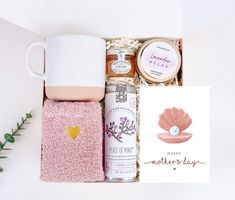 an open gift box containing two mugs, cookies, and other personal care items