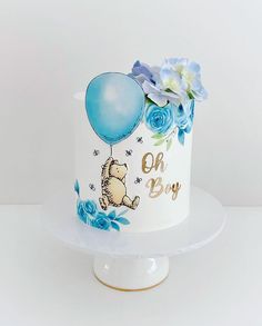 a winnie the pooh birthday cake with blue flowers and balloons