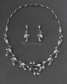 a necklace and earring set with leaves on the front, in white gold plated