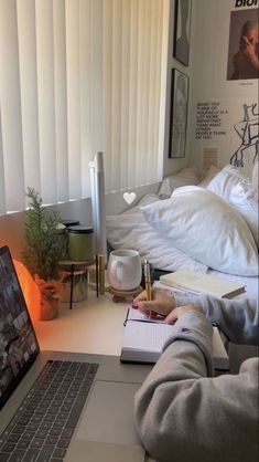 a person sitting in front of a laptop computer on a desk next to a bed