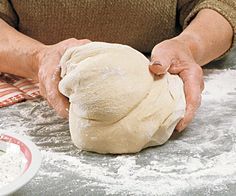 a person kneading dough on top of a table